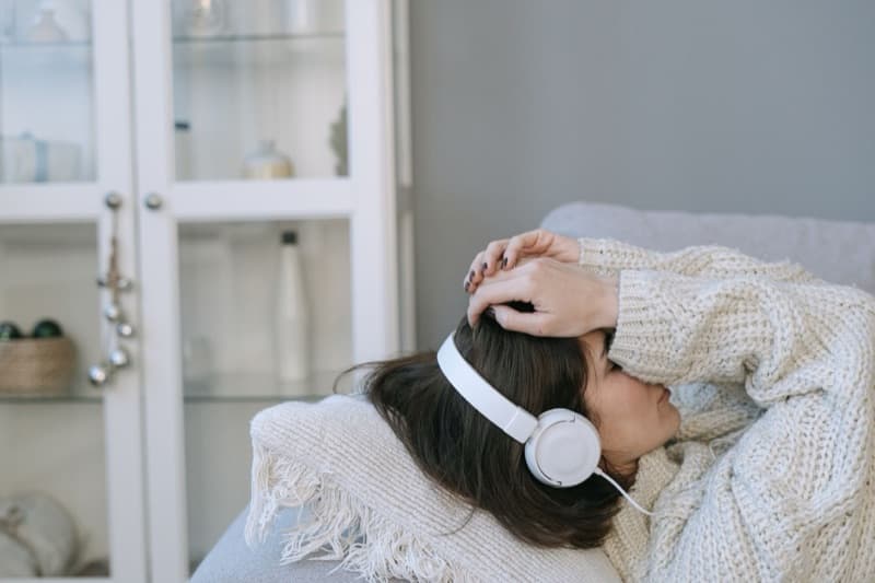 Woman resting with headphones on, using gentle sound enrichment to ease tinnitus after sudden hearing loss.