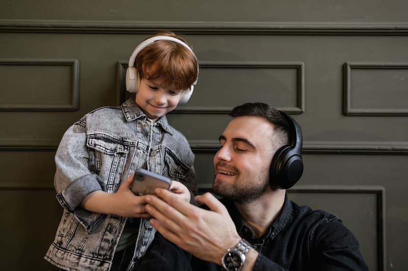 Dad and kid listening to white and brown noise on headphones.